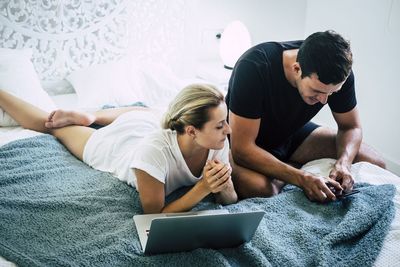 Young man using mobile phone while sitting on bed