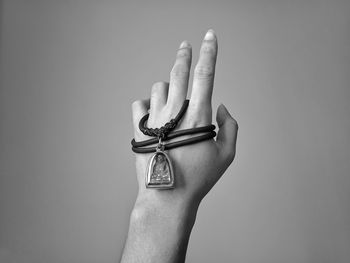 Close-up of human hand with locket against gray background