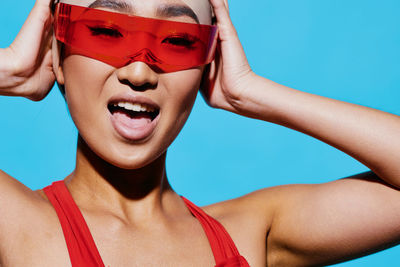 Close-up of woman wearing sunglasses against blue sky