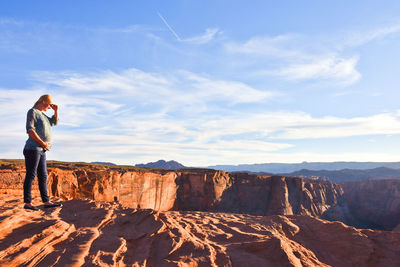 Full length of pregnant woman standing on rock at horseshoe bend against sky