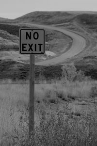 Road sign on field against sky