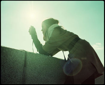 Low angle view of man holding leaf against sky