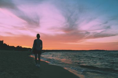 Silhouette of man standing on beach at sunset