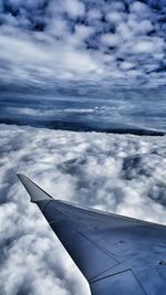 Cropped image of airplane against cloudy sky
