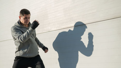 Side view of man standing against wall