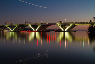 Illuminated bridge over river against sky at night