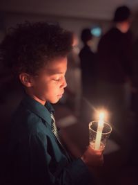 Close-up of man holding illuminated candle