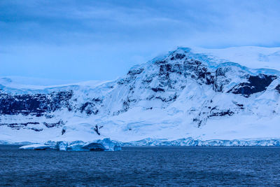 Scenic view of snowcapped mountains by sea against sky