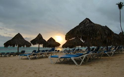 Deck chairs on beach against sky