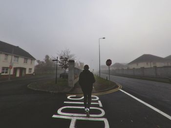 Man walking on road against sky