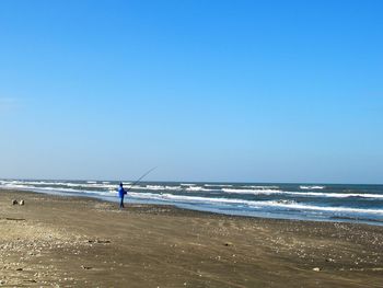 Man on beach against clear blue sky