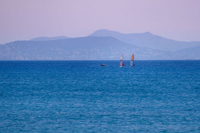 Windsurfers on sea against clear sky