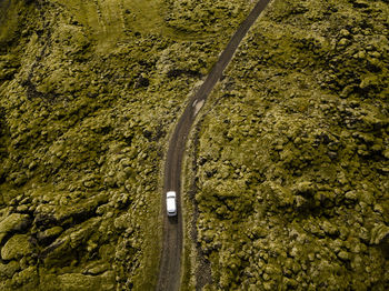 Aerial view of car driving through moss covered lava rocks in ic