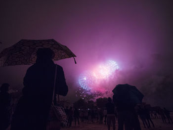 Silhouette people watching firework display at night