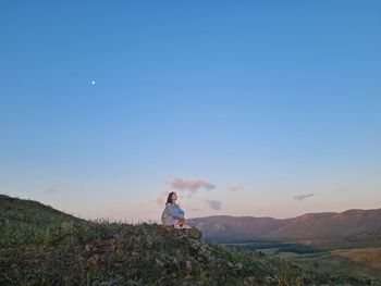 Rear view of women standing on mountain against sky