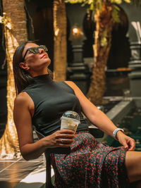 Portrait of young woman sitting on railing