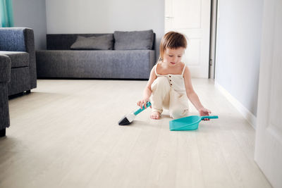 Cute european child with blue scoop  and brush sweeping floor helps clean, development of montessori