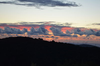 Silhouette landscape against dramatic sky during sunset