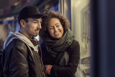 Happy multi-ethnic couple window shopping at dusk