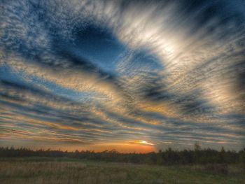 Scenic view of field against dramatic sky during sunset