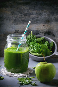 Close-up of spinach smoothie in jar by fruit on table