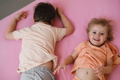 Kids playing on colorful bed in the morning hide-and-seek. happy child lie on pink bed. sister and