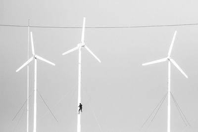 Low angle view of person climbing on wind turbine