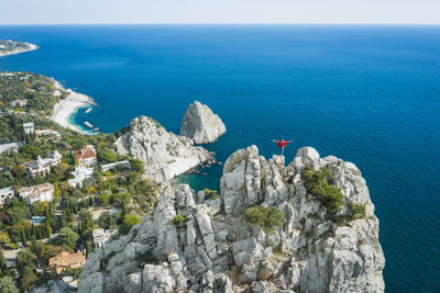 Man tourist in red jacket standing on the rock top of cat mountain enjoying  simeiz area. crimea