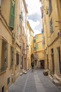 Rear view of man walking on street amidst buildings in city