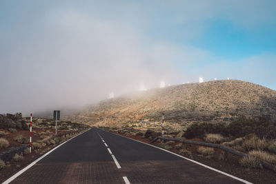 Empty road along landscape against sky