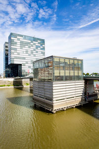 Building by river against sky in city