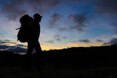 Silhouette female hiker with backpack walking against sky