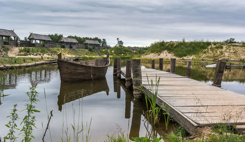 Wooden posts in lake against sky