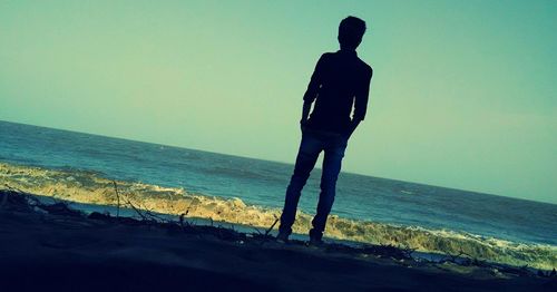 Silhouette man standing at beach against clear sky