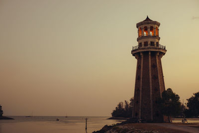 Lighthouse by sea against clear sky