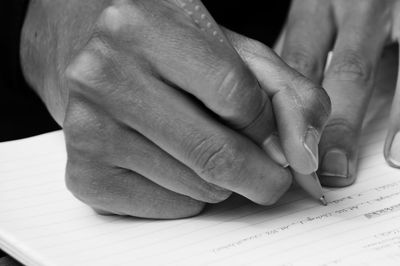 Cropped image of hand writing on book