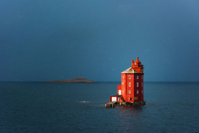 Lighthouse by sea against sky