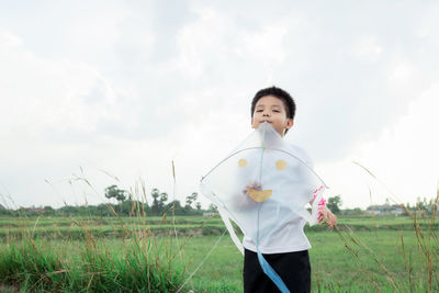 Boy standing on field against sky