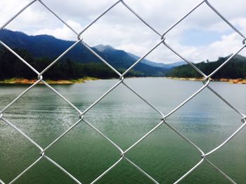 Scenic view of lake seen through chainlink fence