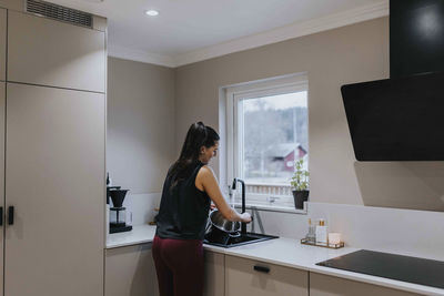 Woman washing dishes in kitchen