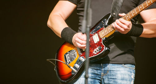 Midsection of man playing guitar at concert