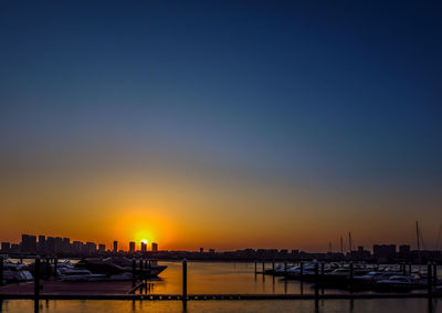 Boats moored at harbor during sunset