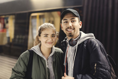 Portrait of happy young couple standing at subway station
