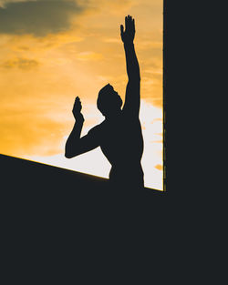 Silhouette man and woman standing against orange sky