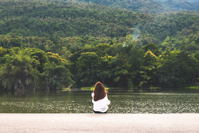 Rear view of woman looking at lake against mountain