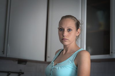 Portrait of woman standing against cabinets at home