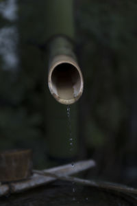 Close-up of water drop from faucet against blurred background