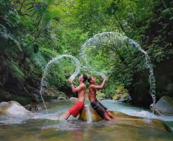 Full length of shirtless man and woman in forest