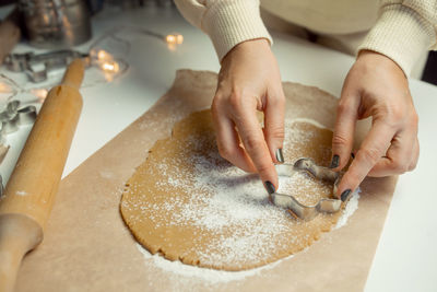 Hands make star-shaped cookies from dough on baking paper