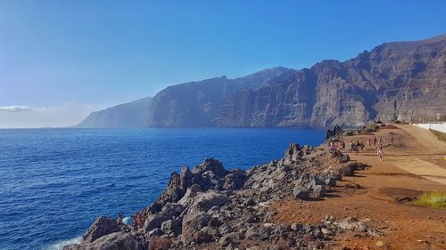 Scenic view of rocky cliff against clear blue sky